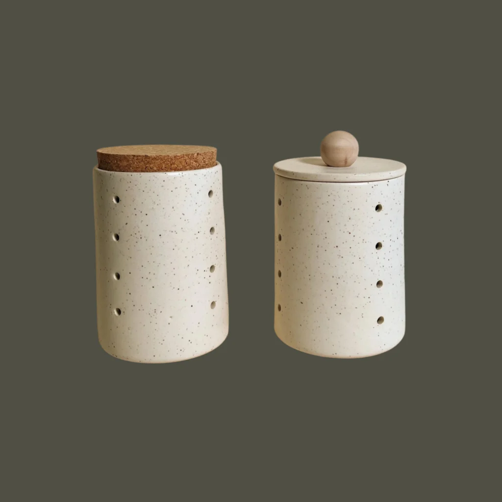 Two speckled ceramic canisters with perforated sides, one with a cork lid, from Tellefsen Atelier